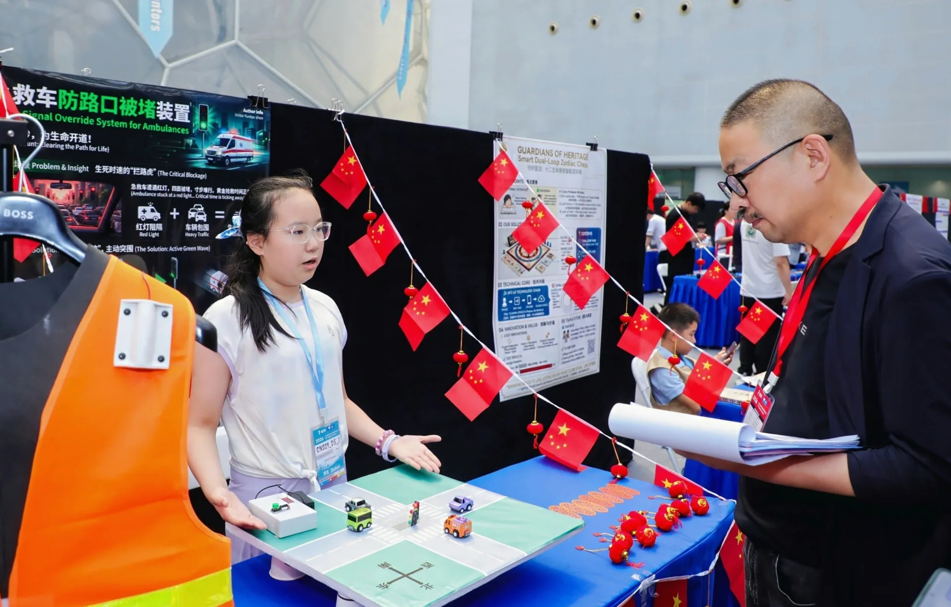 A judge reviews a young inventor's smart traffic-safety project at IEYI 2026